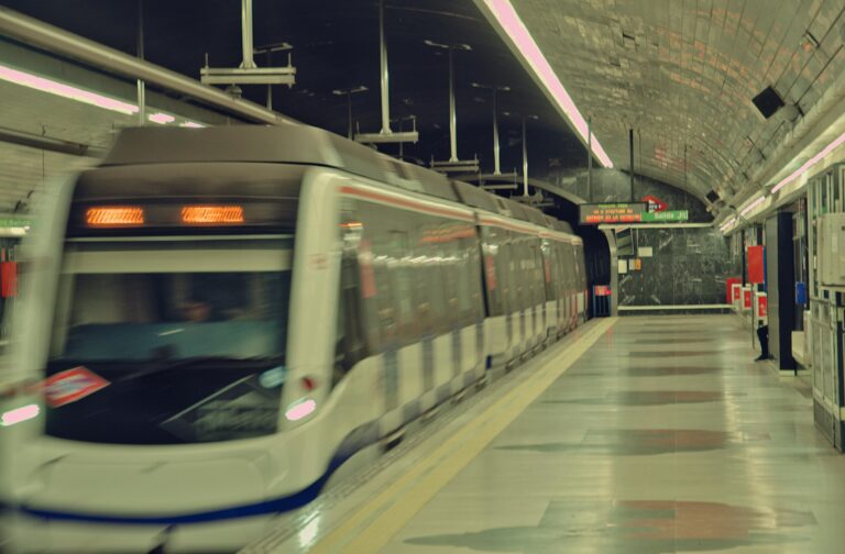 High-speed train departing a dimly lit subway station in Madrid at night, showcasing urban transit.